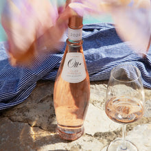 Load image into Gallery viewer, A bottle of rose wine and a glass standing on a stone table.