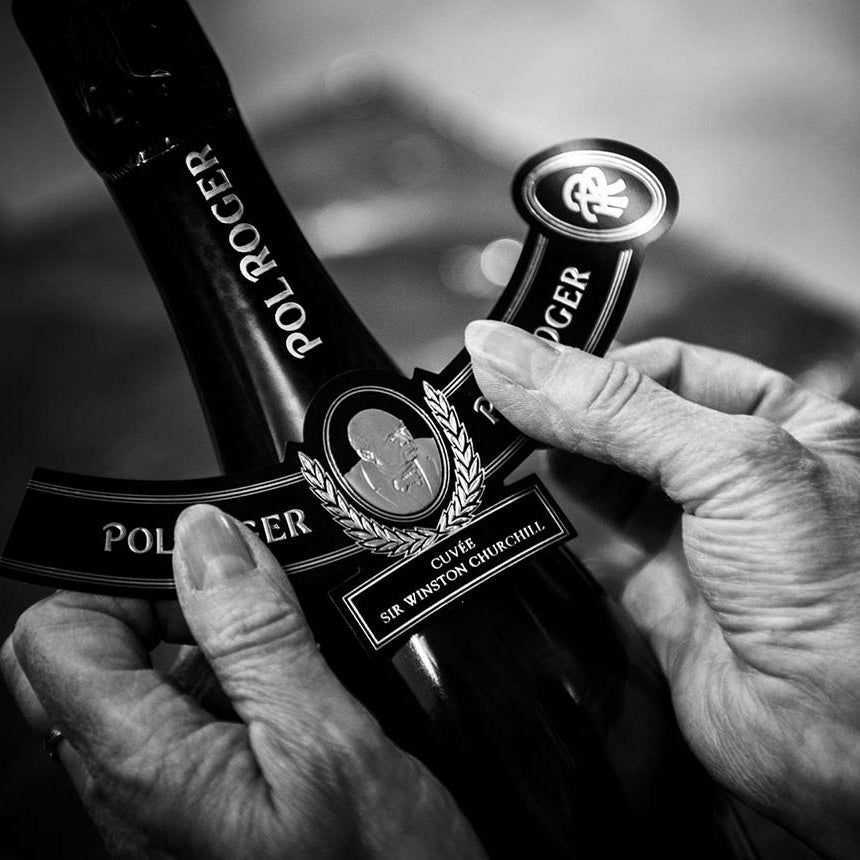Load image into Gallery viewer, A woman attaching a label by hand on a bottle of POL ROGER Cuvée Sir Winston Churchill Champagne