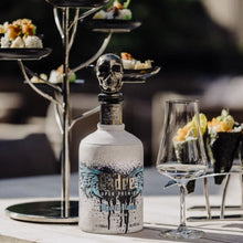Load image into Gallery viewer, Bottle of Padre-Azul-Blanco-Tequila with a skull design on a table with a blurred background