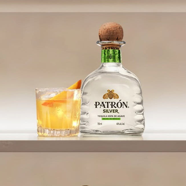 Load image into Gallery viewer, Patrón Silver tequila bottle with orange cocktail glass on a shelf.