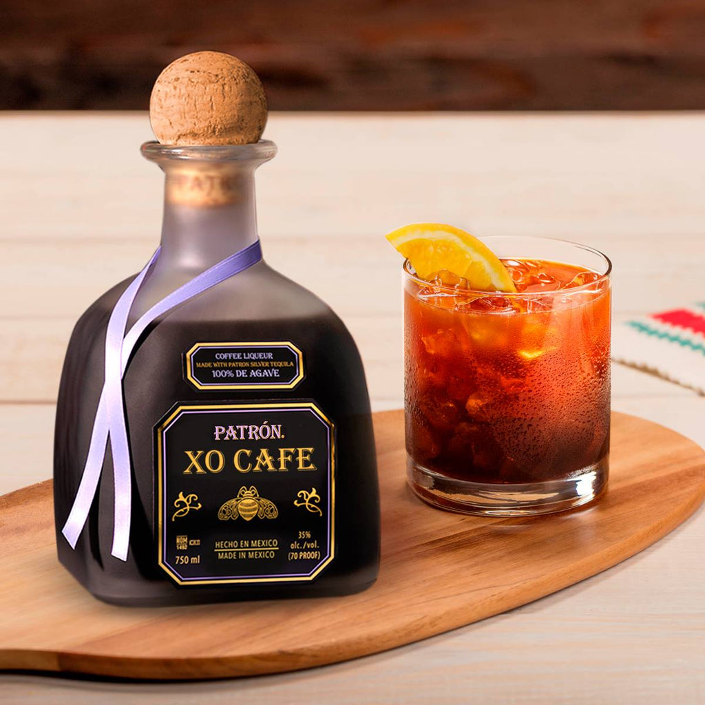 Patrón XO Cafe bottle with a glass of red cocktail on a wooden board