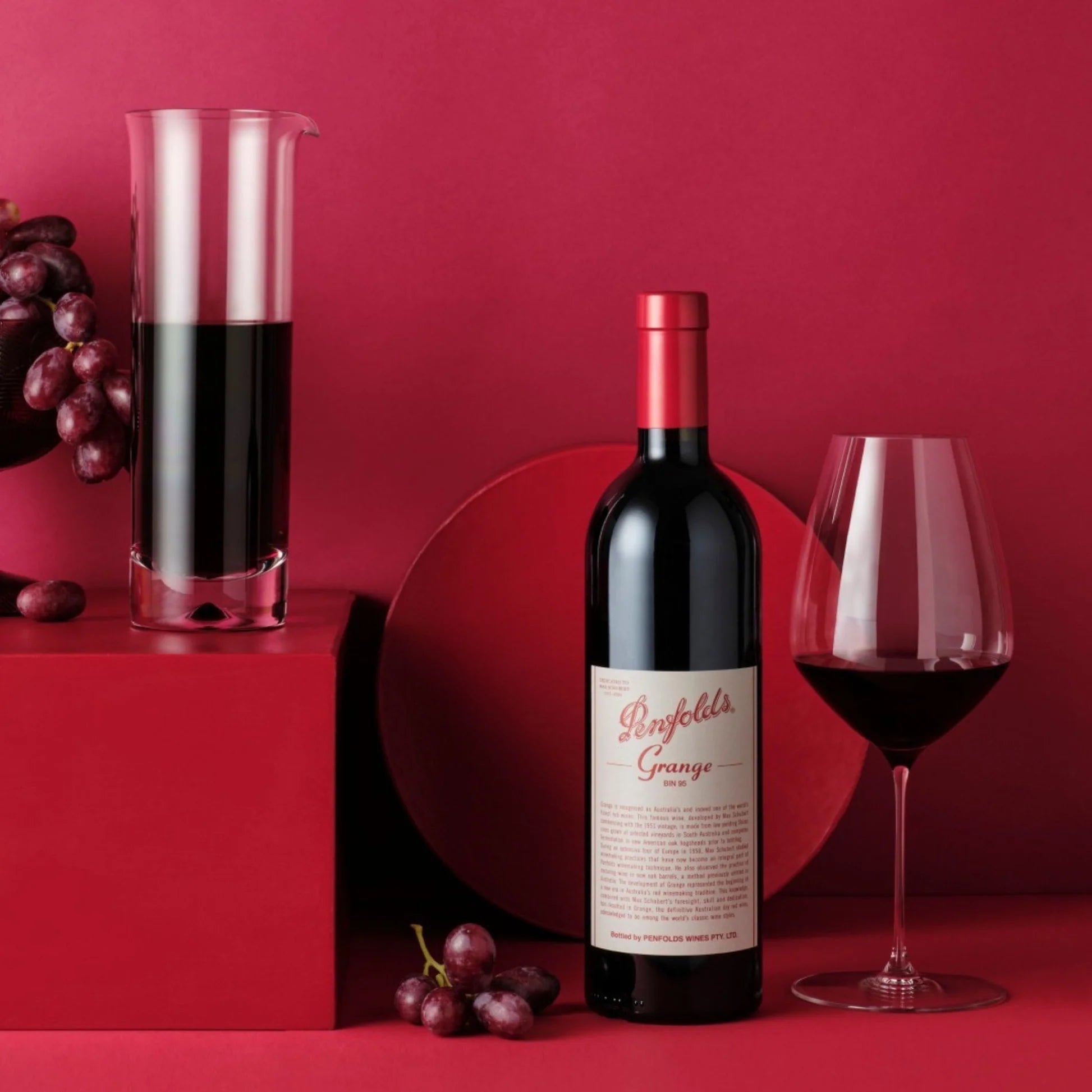 Load image into Gallery viewer, Penfolds Grange wine bottle with a glass of red wine on a red background