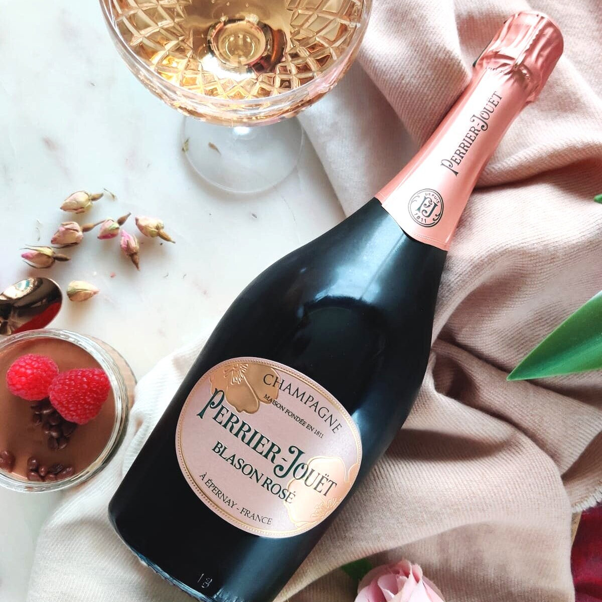 Load image into Gallery viewer, Bottle of champagne with a glass and flowers on a table.