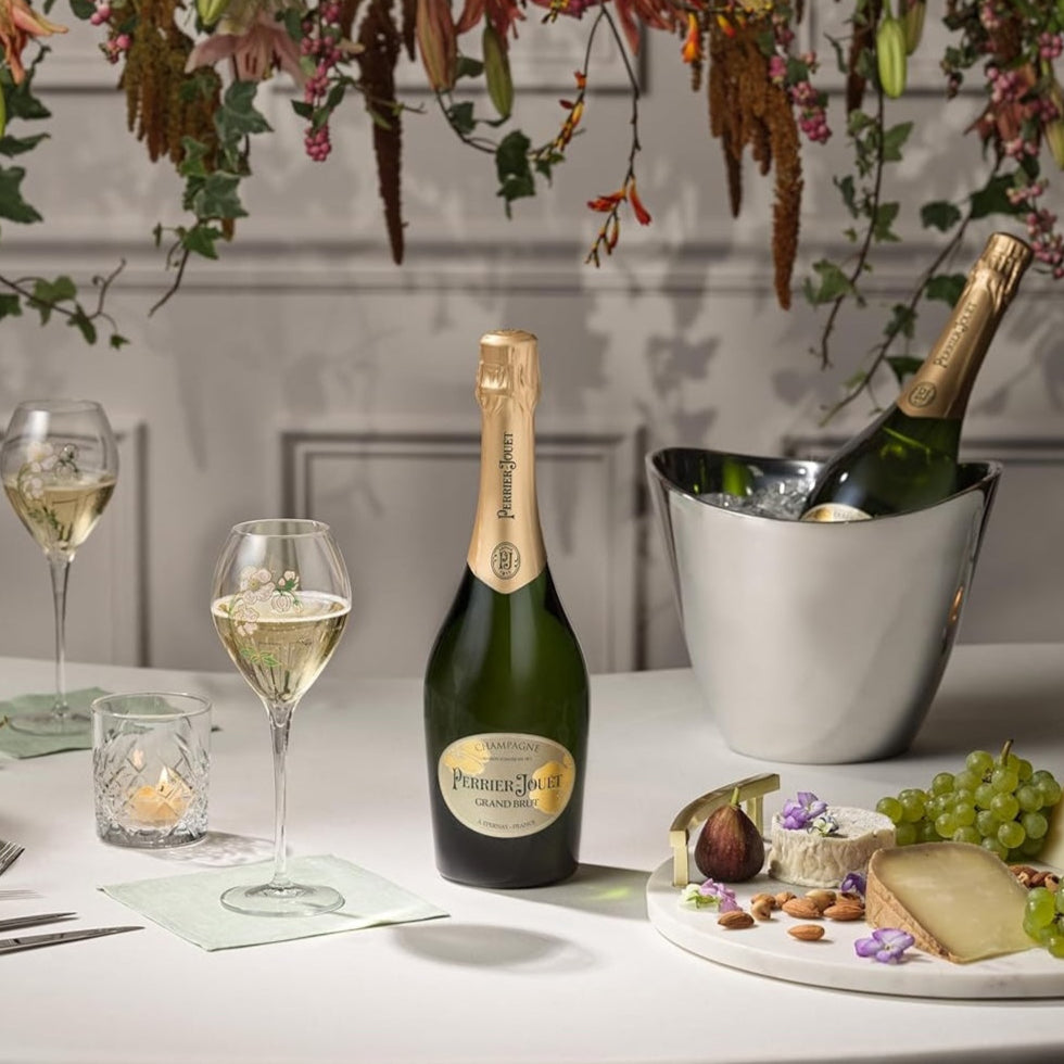 Load image into Gallery viewer, Champagne bottles and glasses on a table with cheese and grapes.