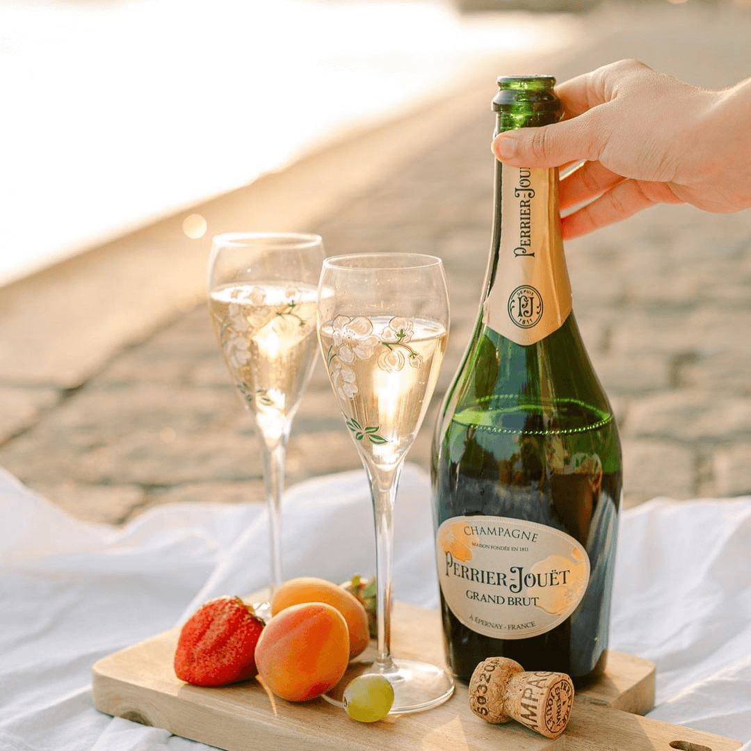 Load image into Gallery viewer, Champagne bottle and glasses on a wooden board with fruits.