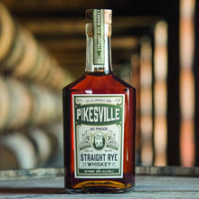Load image into Gallery viewer, A bottle of Pikesville Whiskey standing on a barrel with barrels in the background