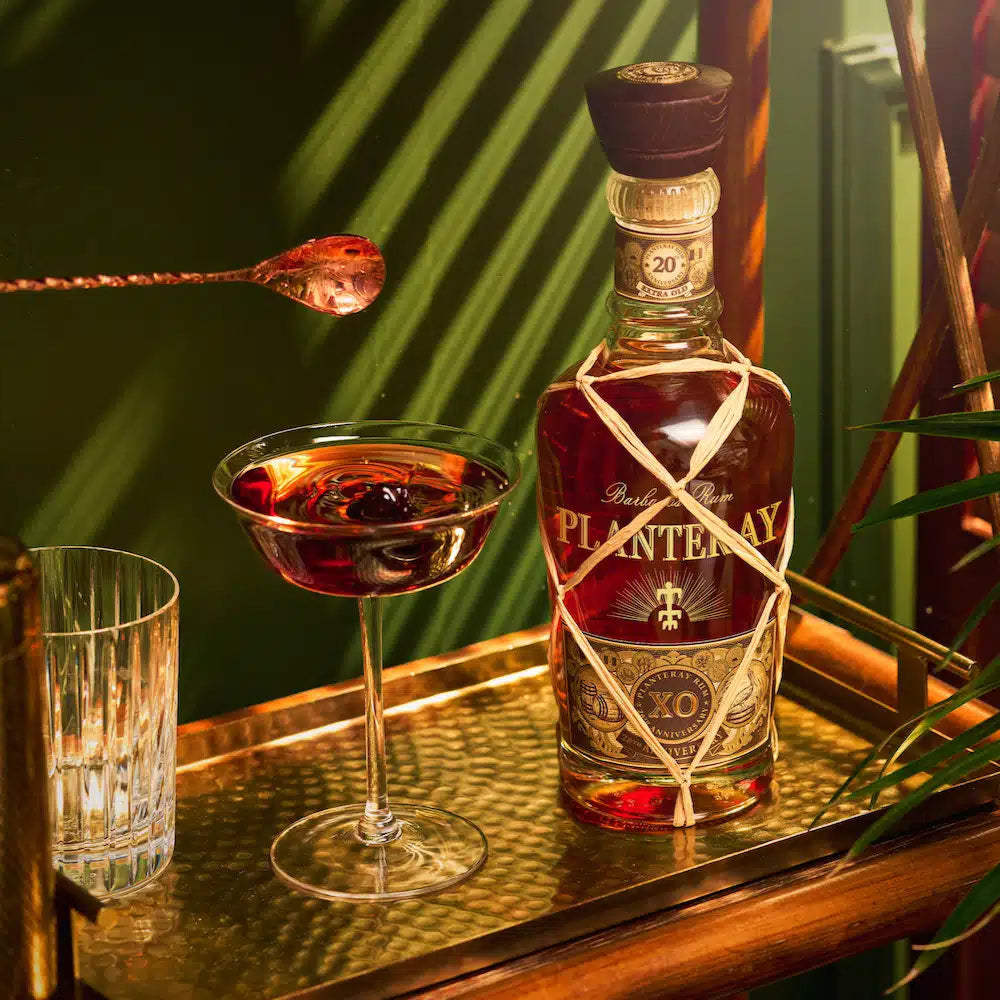 Load image into Gallery viewer, Bottle of Plantation Planteray XO rum with a cocktail glass and bar tools on a reflective surface.