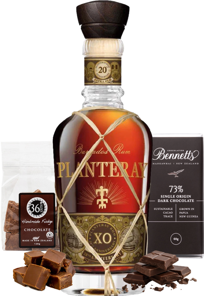 A bottle of Planteray XO rum centered on a white background, surrounded by chocolate products: a bag of 36 Handmade Fudge chocolate, a box of Bennett 73% single origin dark chocolate, and several chocolate pieces and chunks.
