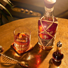 Load image into Gallery viewer, Bottle of Planteray X0 Rum with a glass of whiskey on a wooden table.