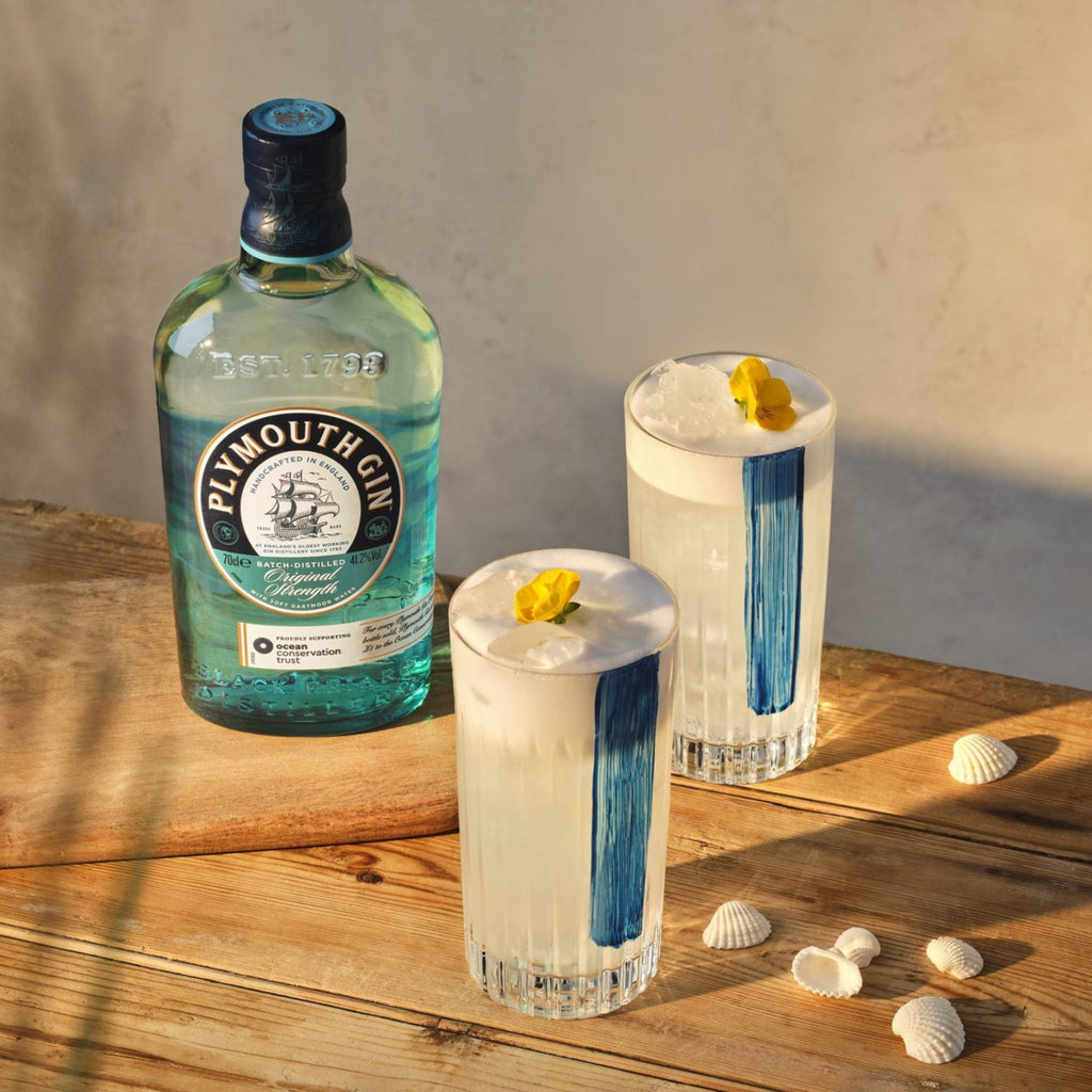 Bottle of Plymouth Gin with two cocktails on a wooden surface