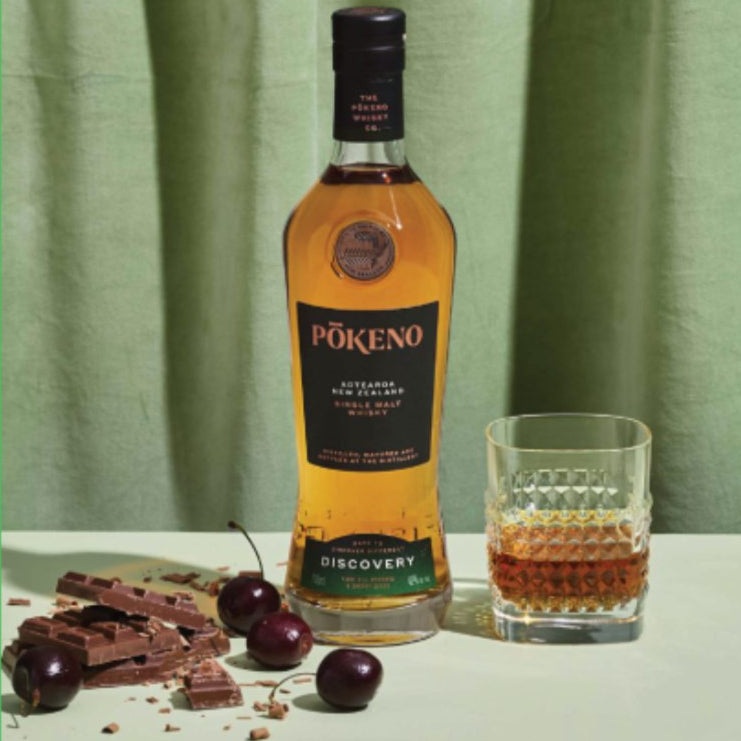 Load image into Gallery viewer, Pokeno Discovery whisky bottle with a glass and chocolate on a green background, featuring 'World of Whisky' branding.