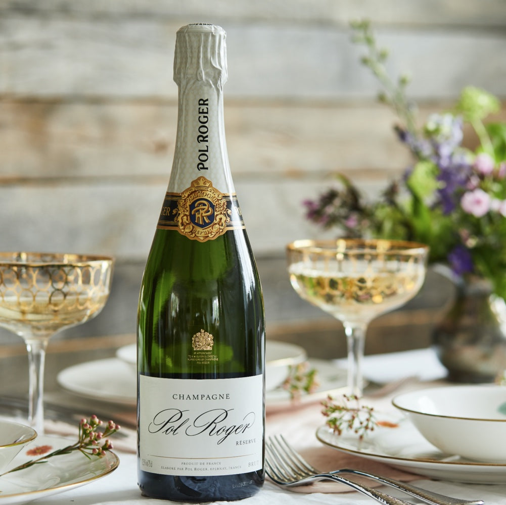 Load image into Gallery viewer, Bottle of Pol Roger champagne on a table with glasses and flowers