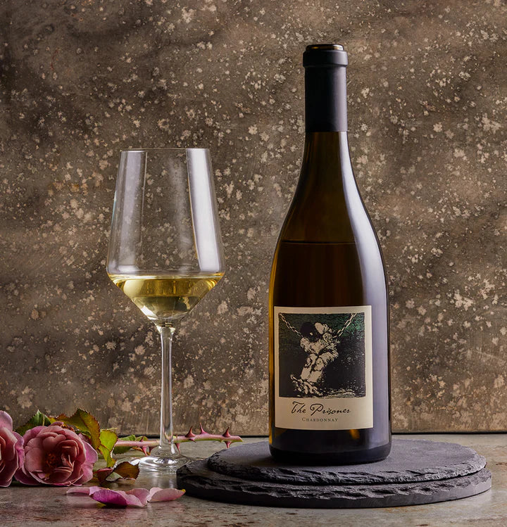 Load image into Gallery viewer, A bottle of chardonnay wine and a glass of wine on a marble table with pink roses in the background
