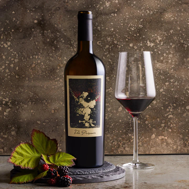 The Prisoner Red Blend wine bottle with label and glass of red wine on a textured surface