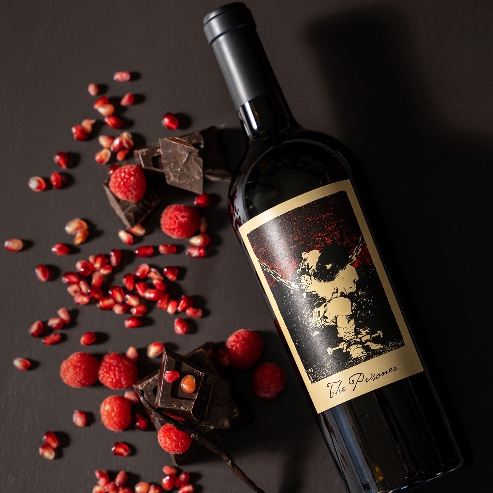 Load image into Gallery viewer, A bottle of The Prisoner Red Blend lying next to delicious looking fresh berries and dark chocolate.