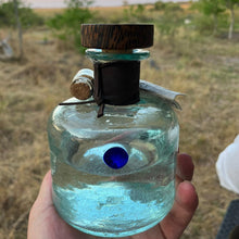Load image into Gallery viewer, A bottle of Procera Blue Dot-Kenyan Gin with a wooden stopper held in a hand against a natural background