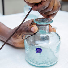 Load image into Gallery viewer, Man crafting a bottle of Procera Blue Dot-Kenyan Gin, attaching a leather strap to the top of the bottle