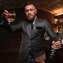 Load image into Gallery viewer, Conor Mcgregor holding a neat glass of whiskey in his hand and the bottle of whiskey in his other hand