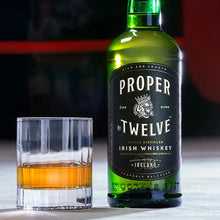 Load image into Gallery viewer, A bottle of Proper Twelve Irish Whiskey  on a white table and a neat glass of whiskey 