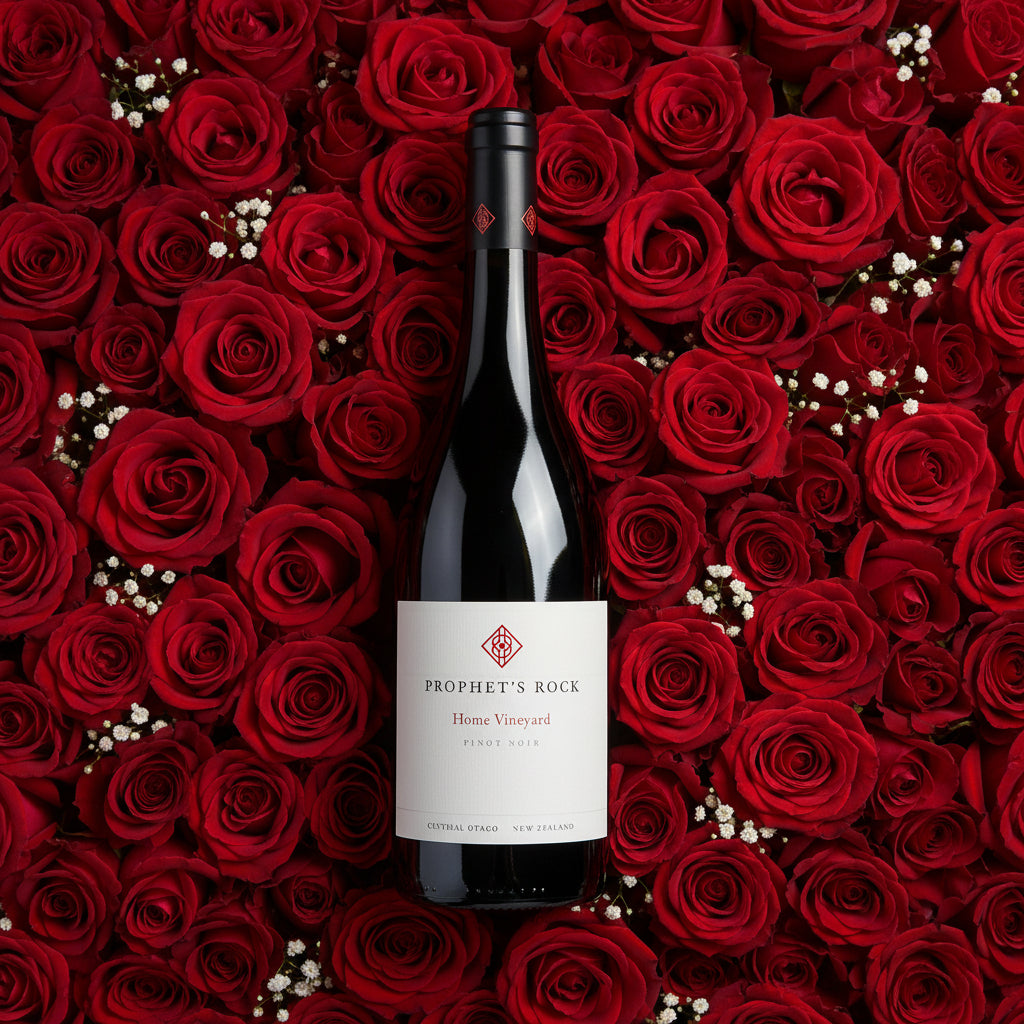 Load image into Gallery viewer, A bottle of Prophet’s Rock Home Vineyard Pinot Noir red wine centred against a dense background of red roses with small white filler flowers.