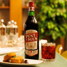 Load image into Gallery viewer, Bottle of Punt e Mes with a glass of red drink on a table.