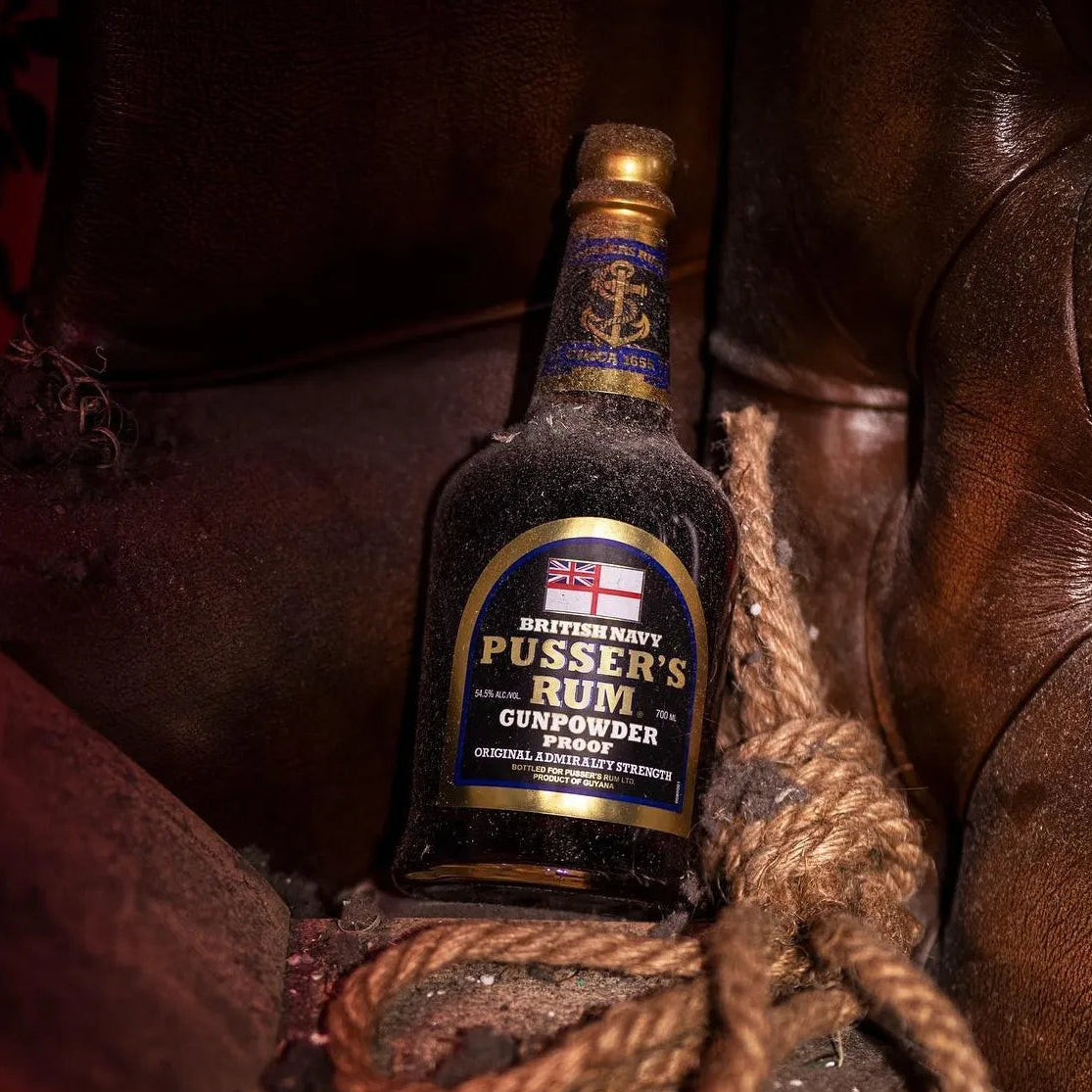 Load image into Gallery viewer, Bottle of Pusser’s Gunpowder Proof Rum on a leather surface with a rope