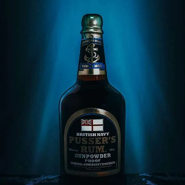 Load image into Gallery viewer, Bottle of Pusser’s Gunpowder Proof Rum on a dark blue background, as if submerged in the ocean