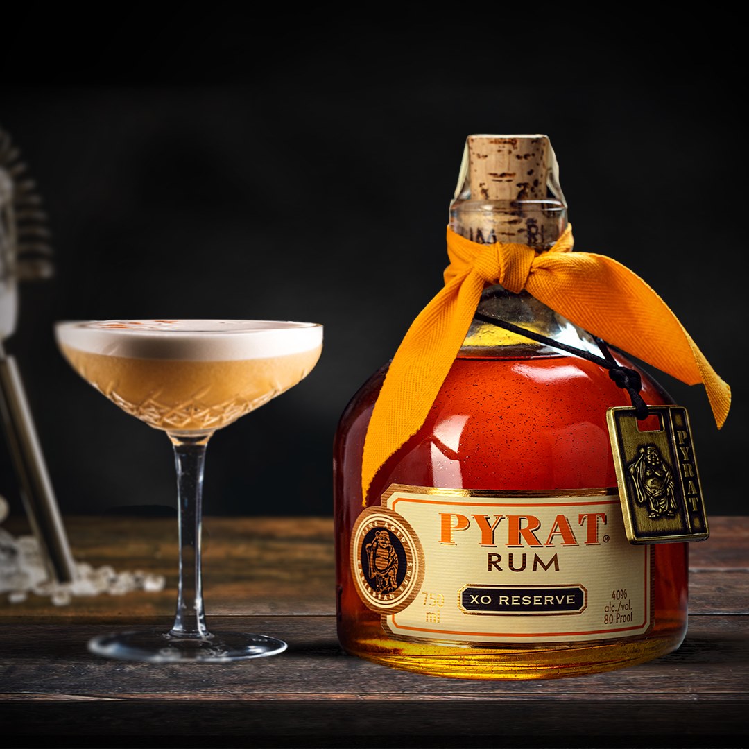 Load image into Gallery viewer, Bottle of Pyrat XO Reserve Rum with a cocktail on a wooden surface