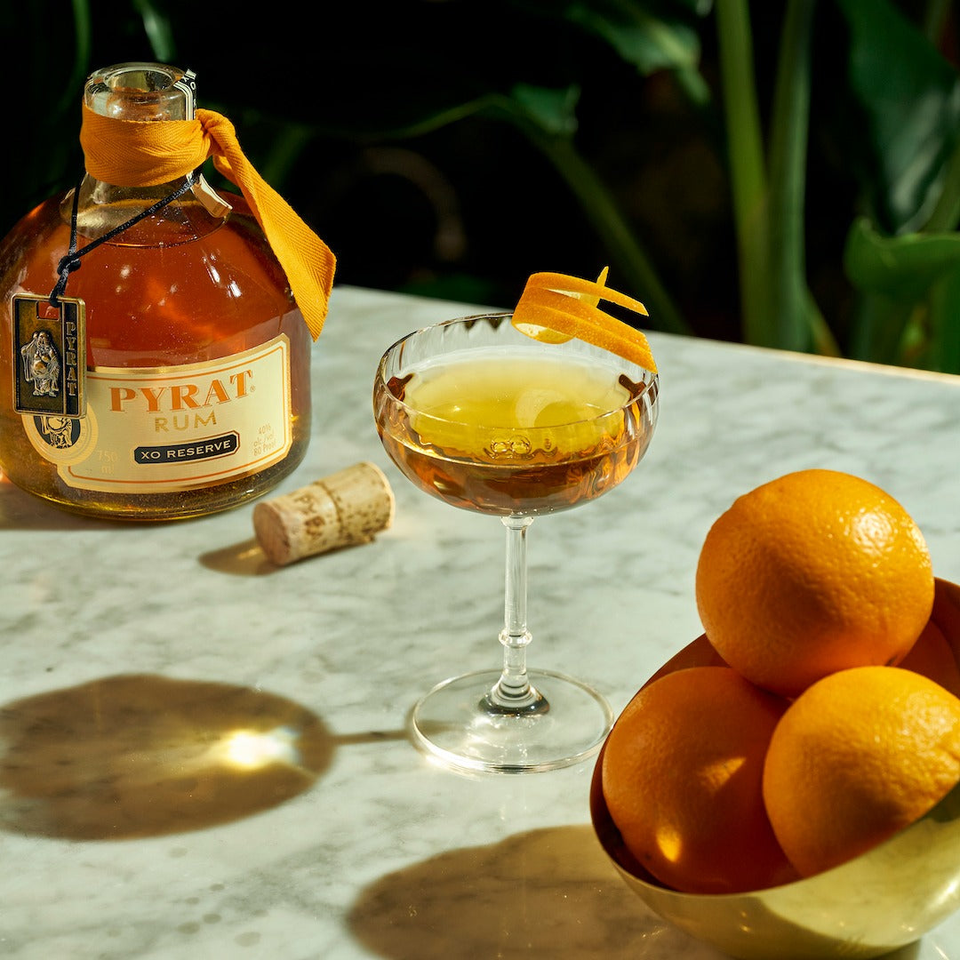 Load image into Gallery viewer, Pyrat XO Reserve Rum bottle with a cocktail and oranges on a marble surface