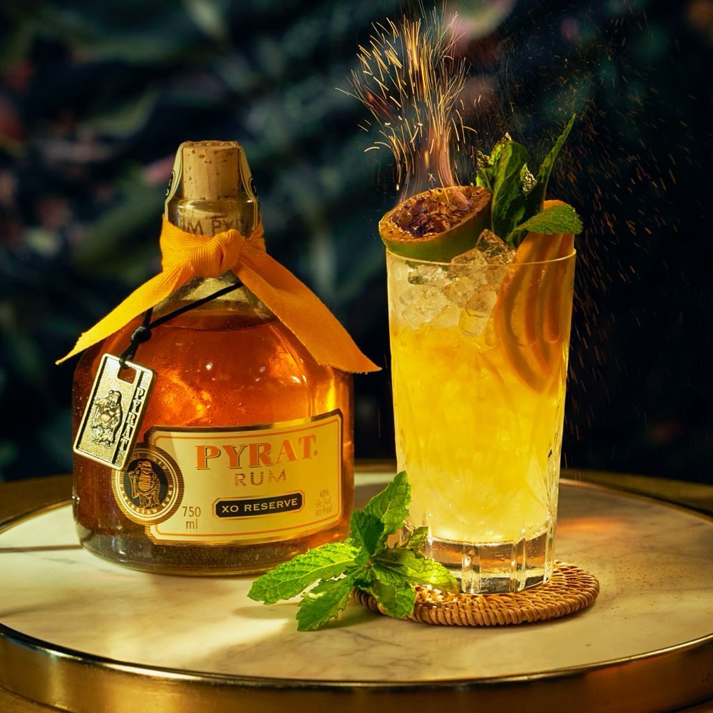 Load image into Gallery viewer, Pyrat XO Reserve Rum bottle with a cocktail garnished with lime and mint leaves on a marble surface.
