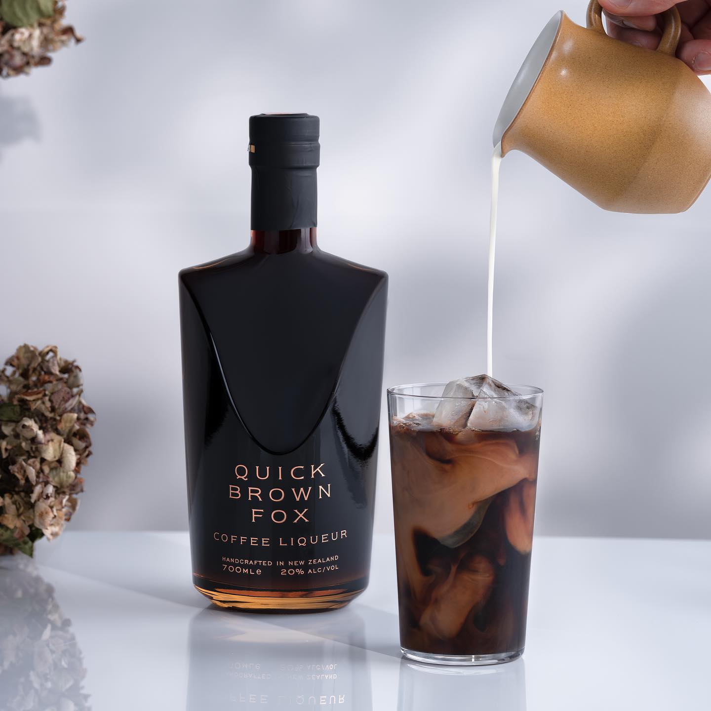 Load image into Gallery viewer, A bottle of Quick Brown Fox Coffee Liqueur and a coffee drink on a white surface 