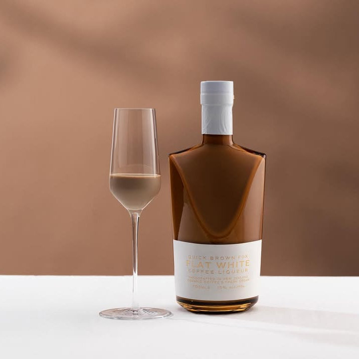 Bottle and glass of Quick Brown Fox 'Flat White' Coffee Liqueur on a neutral background