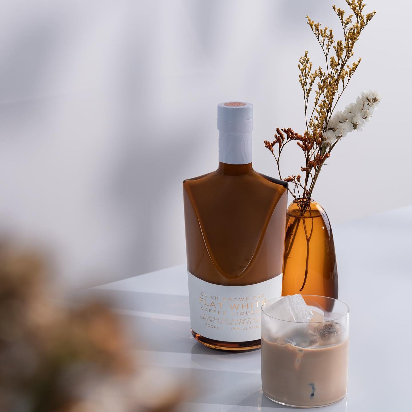 Load image into Gallery viewer, Bottle of Quick Brown Fox 'Flat White' Coffee Liqueur with a dink on a table with a blurred background