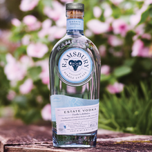 Load image into Gallery viewer, Ramsbury Estate Vodka bottle on a wooden surface with a blurred floral background