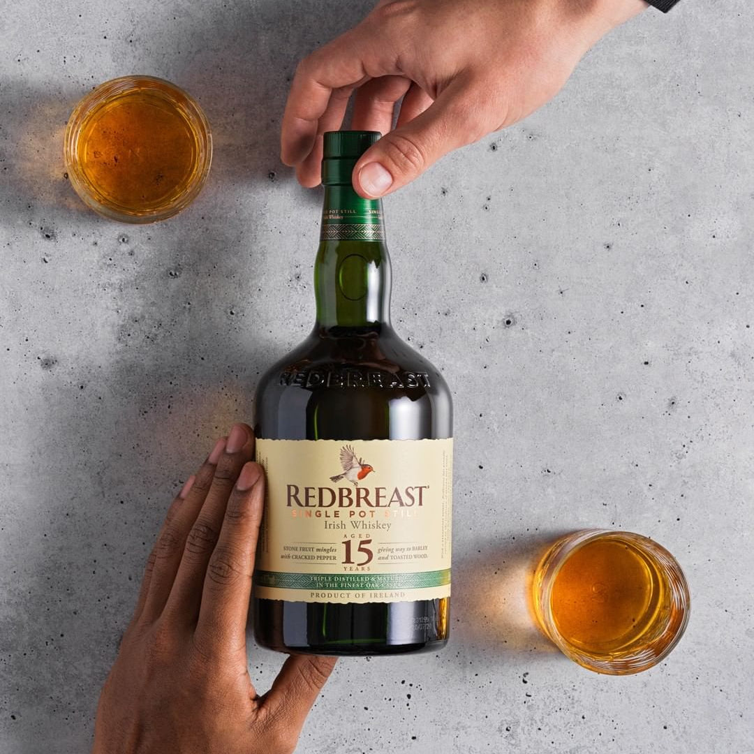 Load image into Gallery viewer, Redbreast whiskey bottle with two glasses on a grey surface