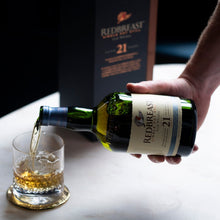 Load image into Gallery viewer, Person pouring Redbreast 21 YEAR OLD whiskey into a glass with a bottle and box in the background.