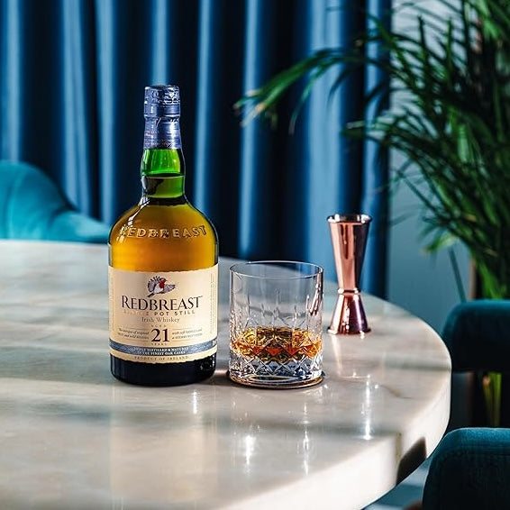 Load image into Gallery viewer, Redbreast 21YO Irish Whiskey and a neat glass of whiskey on a marble table with a blue background