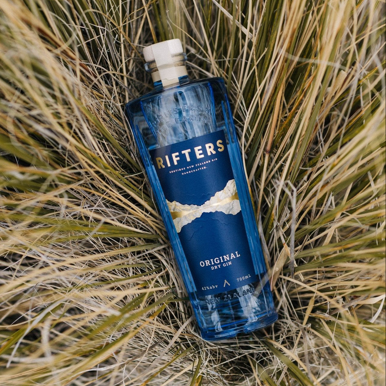 Load image into Gallery viewer, Rifters Original Dry Gin bottle lying on dry grass