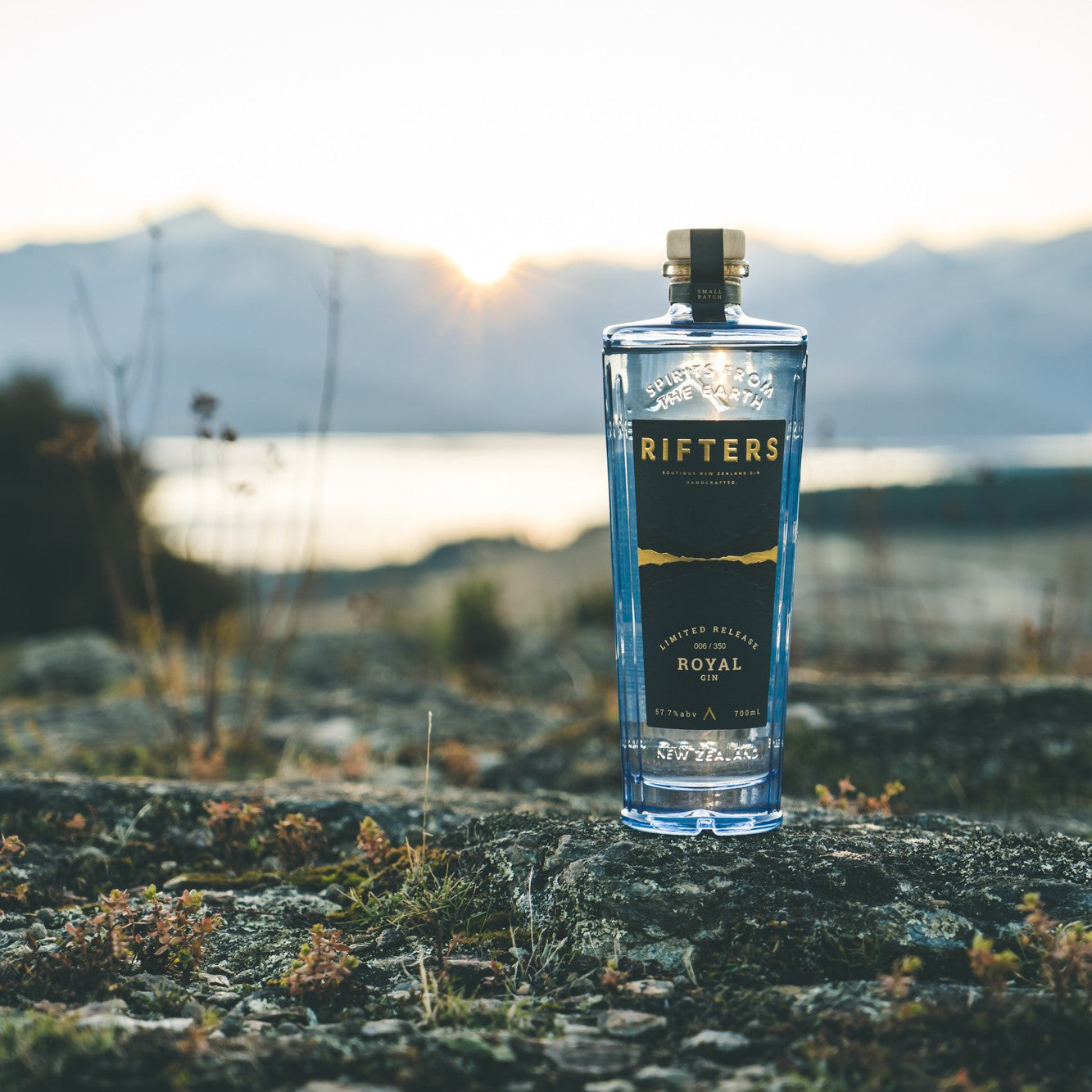 Load image into Gallery viewer, Bottle of Rifters Royal Navy Strength Gin on a rock with a scenic background