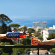 Load image into Gallery viewer, Person pouring a bottle of alcohol into a glass with a scenic background