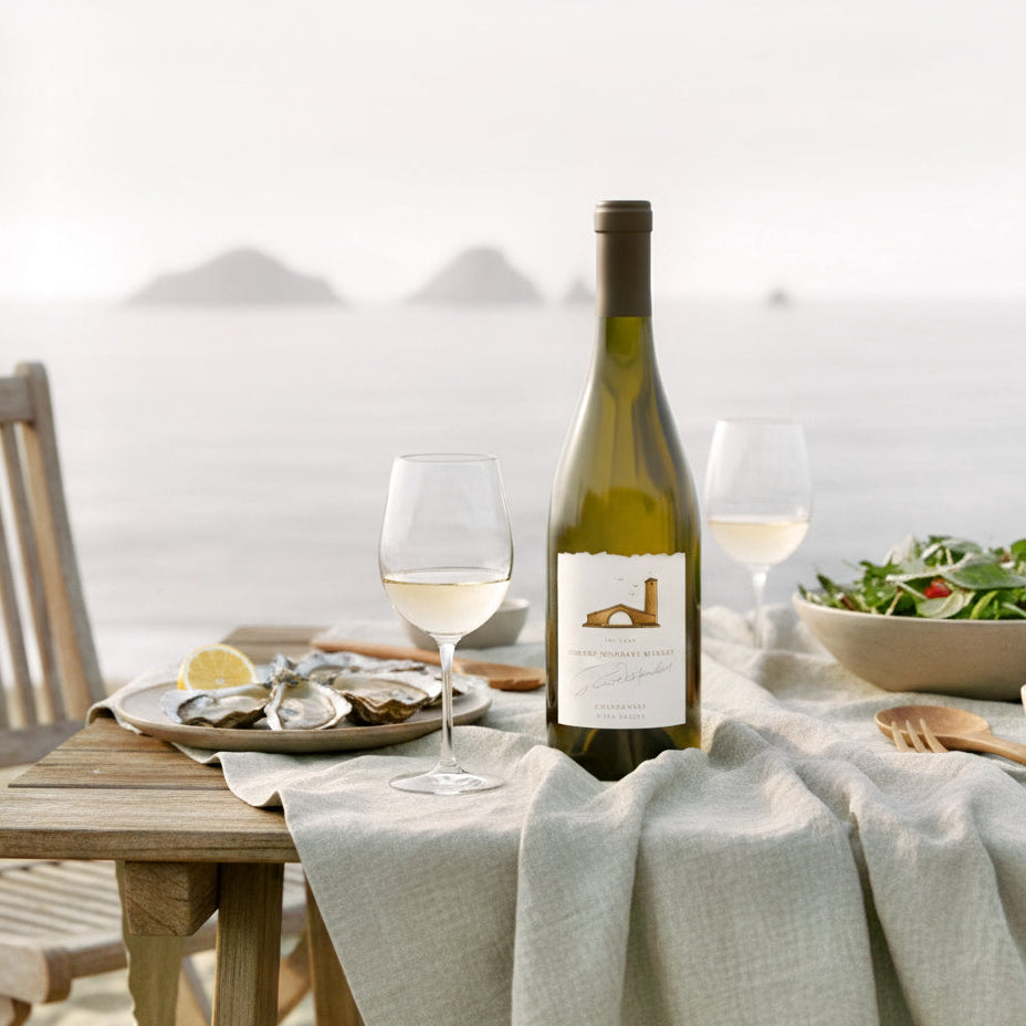 Load image into Gallery viewer, A bottle of Robert Mondavi Napa Chardonnay with a glass of white wine on a table outdoors with a scenic background