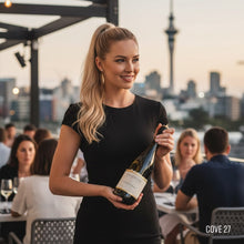 Load image into Gallery viewer, Woman holding a bottle of Rockburn Chardonnay white wine in an outdoor setting with a city skyline in the background