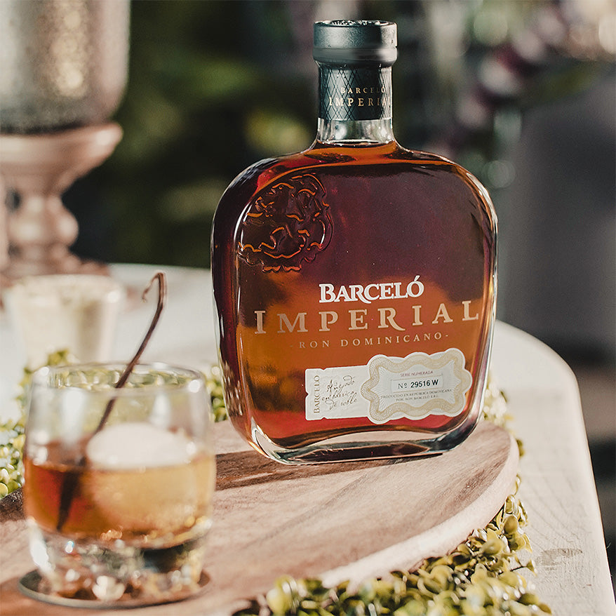 Load image into Gallery viewer, Barceló Imperial rum bottle with a glass of cocktail on a wooden coaster.