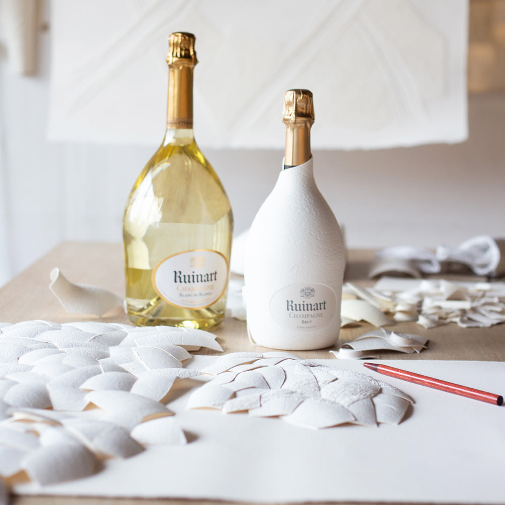 Load image into Gallery viewer, Two bottles of Ruinart champagne on a table with decorative elements.
