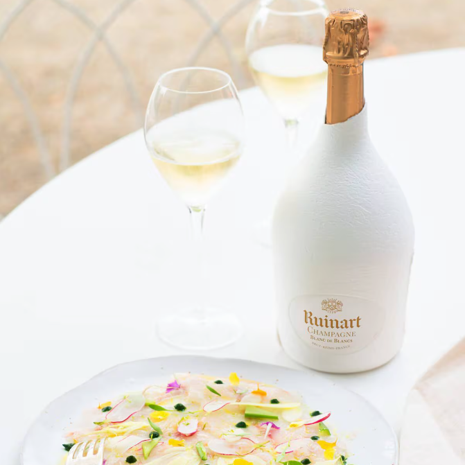 Load image into Gallery viewer, A bottle of champagne and two glasses with some sushi on a white tablecloth with a beige background
