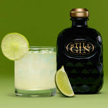 Load image into Gallery viewer, Still Gin bottle and glass with lime garnish on a green background