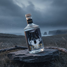 Load image into Gallery viewer, Bottle of Storm Black Wolf gin with a wolf design on a stone in a moody landscape