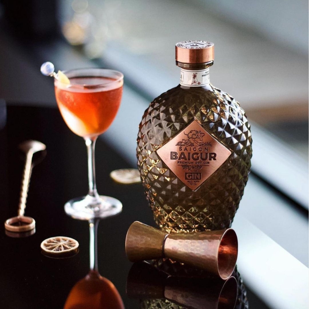 Load image into Gallery viewer, Bottle of Baigour gin with a cocktail and bar tools on a dark surface