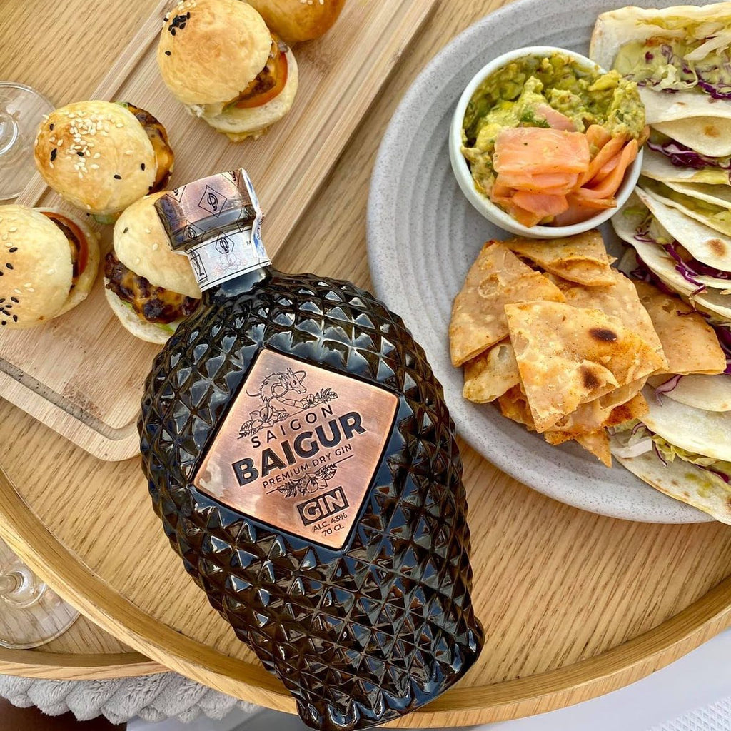 Bottle of Saison Baigur Gin on a wooden tray with appetizers