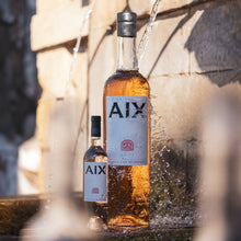 Load image into Gallery viewer, Bottle of AIX wines being poured from a stone fountain.